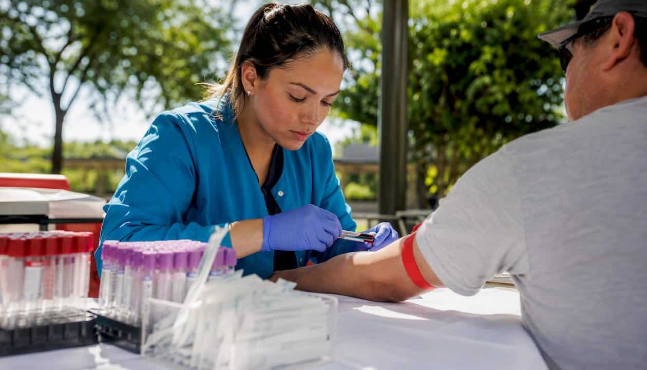 Phlebotomist drawing blood in lab