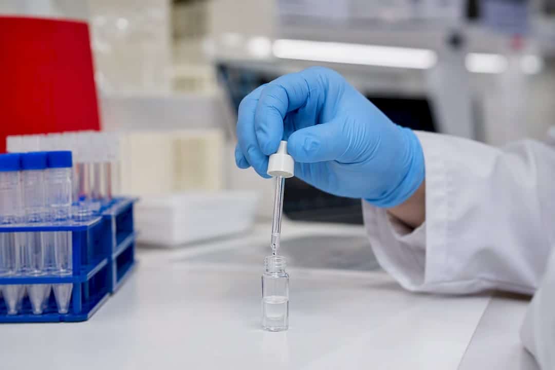 Gloved hand adding reagent to sample vial