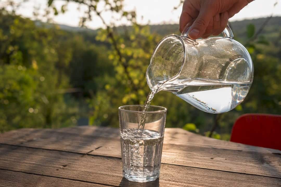 Hand pouring water into glass, hydration context