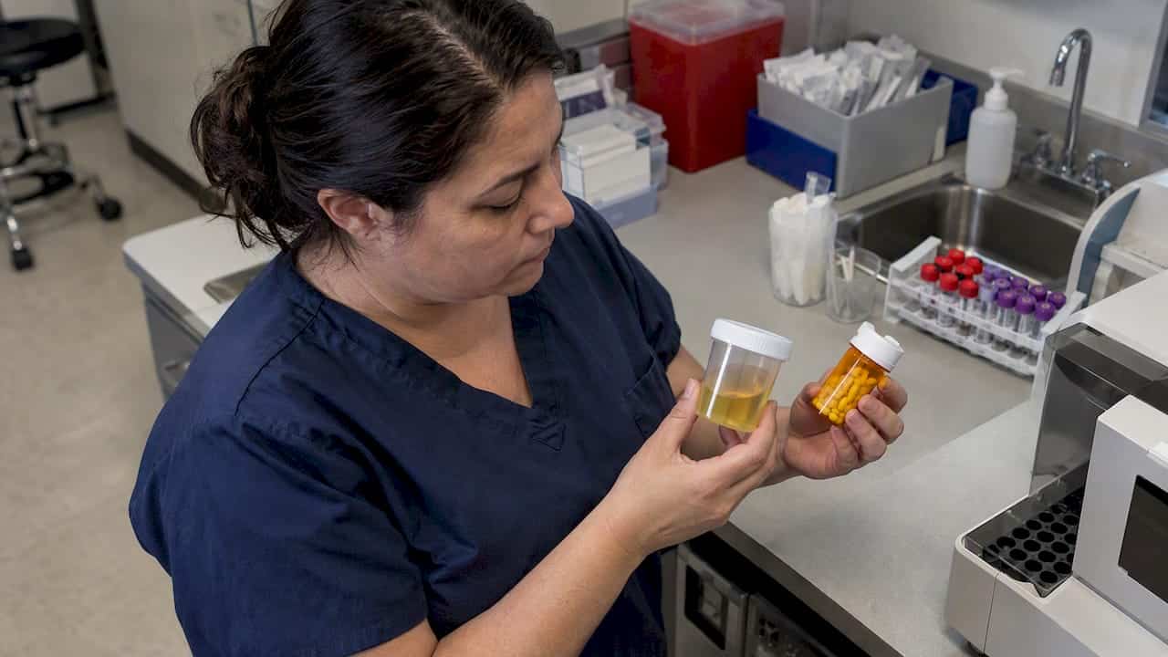 Urine screen cup beside amoxicillin bottle