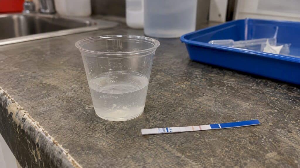Fentanyl test strip beside a dissolved pill sample